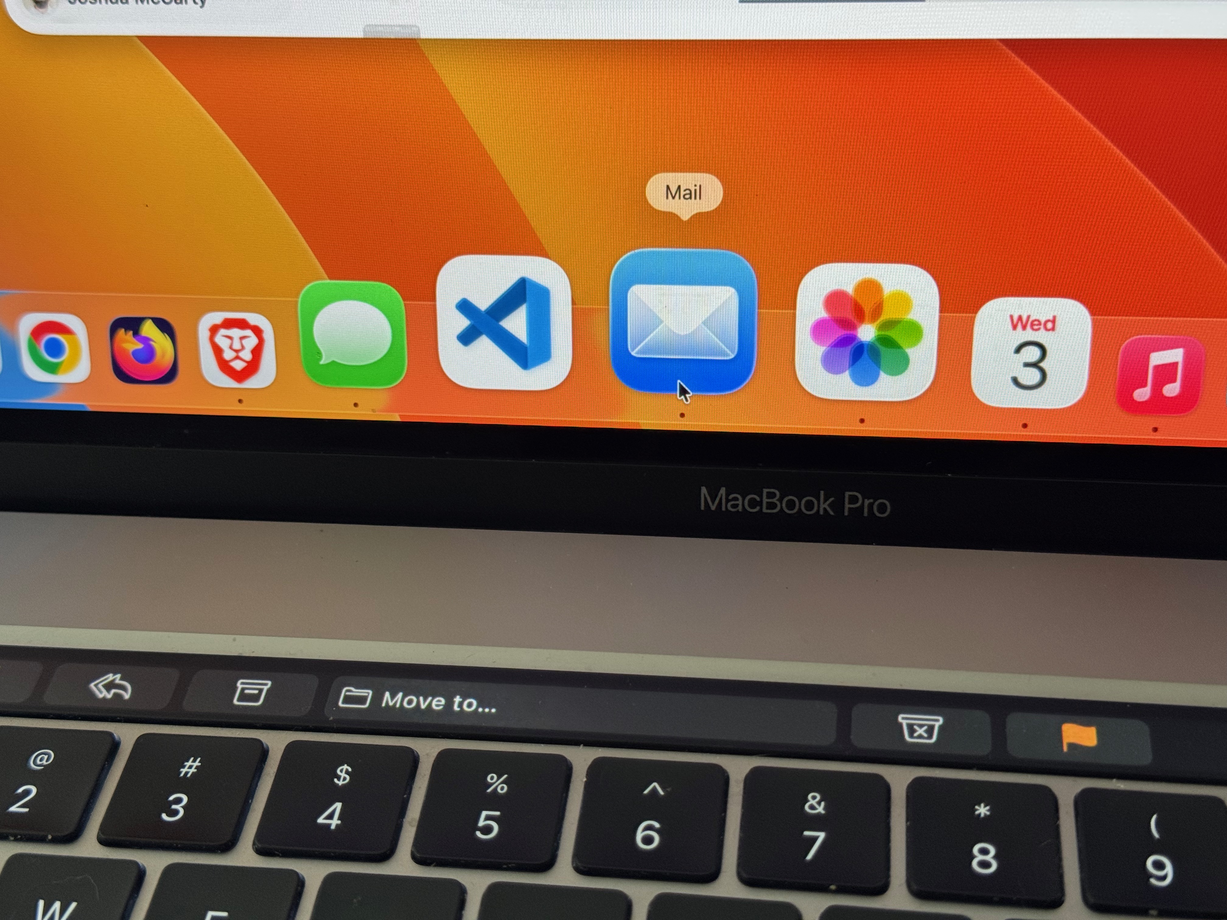 Photo of a MacBook Pro keyboard and bottom of the screen with the mail app icon selected